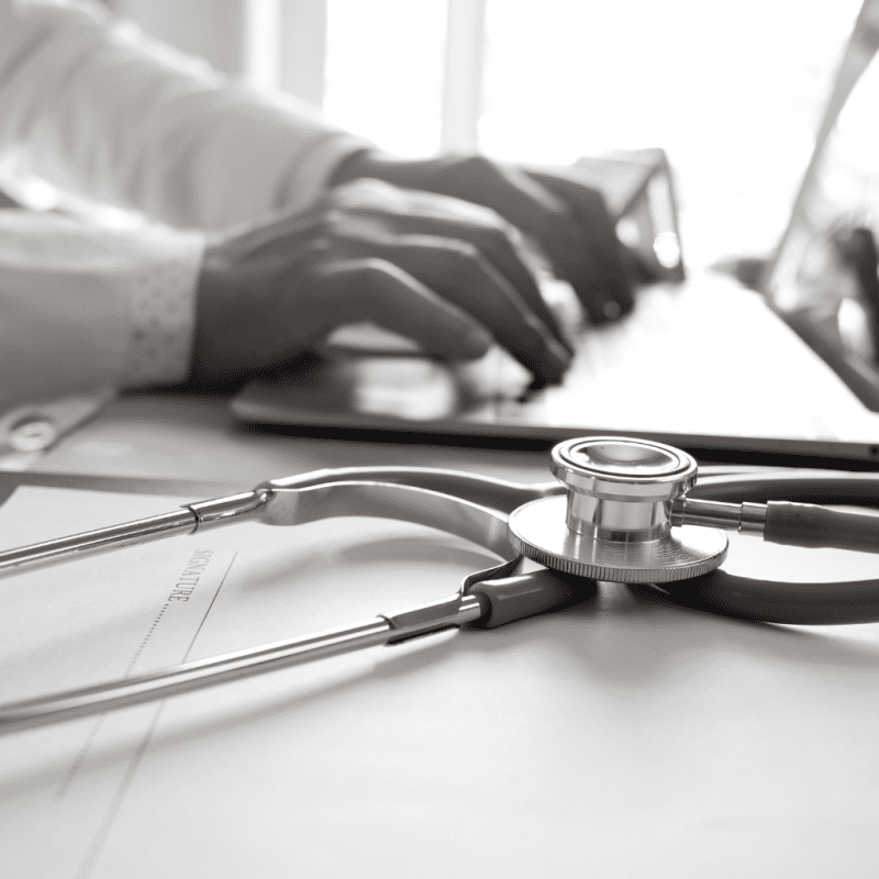 closeup of a doctor typing on a laptop next to a stethoscope