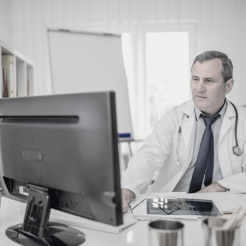 doctor with stethoscope around neck looking at computer monitor